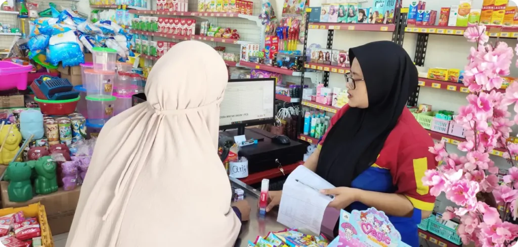 Pembeli dan kasir sedang bertransaksi di toko kelontong sebagai ilustrasi dari 4 tips belanja hemat untuk kebutuhan sehari-hari dan rumah tangga