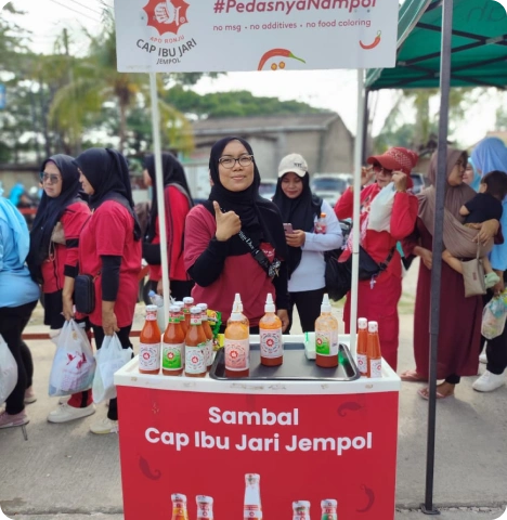 Mitra 7 Booth Sambal Cap Ibu Jari Jempol di event belanja, dengan tim promosi dan pengunjung antre mencicipi.