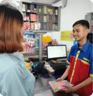 Karyawan Toko Yan tersenyum ramah saat melayani pelanggan di kasir.