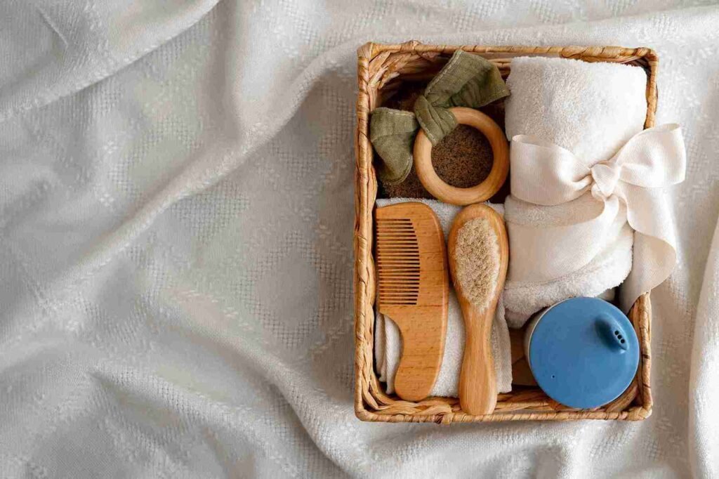 List kado bayi berisi keranjang dengan handuk, sisir, sikat, teether kayu, dan botol biru